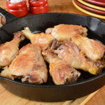 A bunch of pieces of chicken frying in a pan.